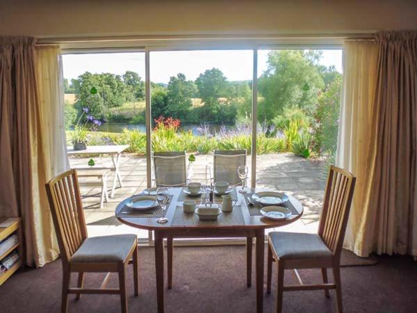 a dining room with a table and chairs and a large window at Herons in Byford