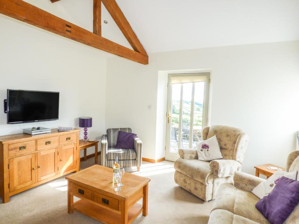 a living room with a couch and a tv at Ghyll Bank Byre in Staveley
