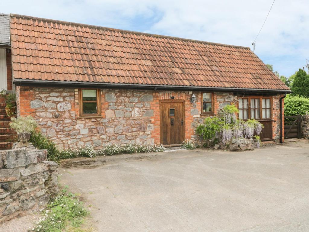 ein altes Steinhaus mit rotem Dach in der Unterkunft High Park Barn in Uffculme