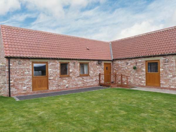 a brick building with a grass yard in front of it at Cooper Cottage in Potto