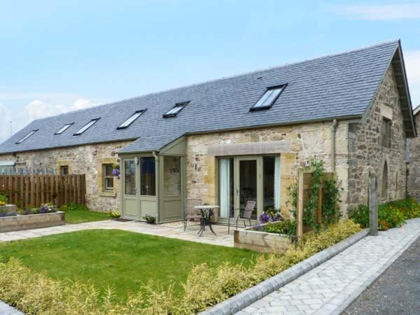 uma casa de pedra com painéis solares em cima em Muirmailing Cottage em Plean