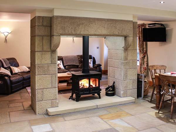 a living room with a stone fireplace in a living room at Orcaber Cottage in Austwick