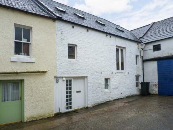 a white building with a garage and a blue door at The Old Brewery Store in Gatehouse of Fleet