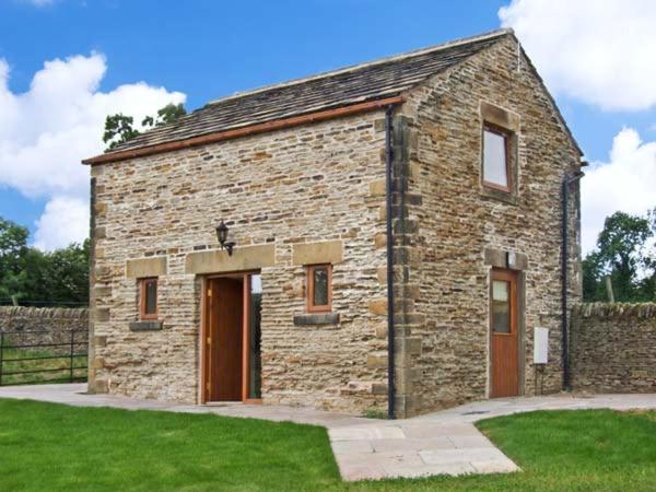 un bâtiment en briques avec deux portes dans une pelouse dans l'établissement Hollins Wood Bothy, à Wortley