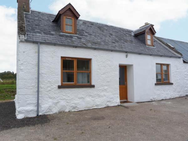 uma casa branca com janelas castanhas e uma porta em The Croft House em Muir of Ord