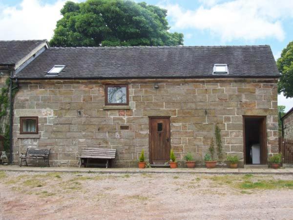 um pequeno edifício de tijolos com um banco e uma janela em Horse Shoe Cottage em Bradley in the Moors