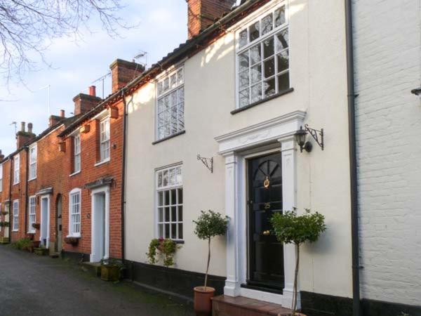 a white building with two potted plants on a street at Ted's Place in Aylsham