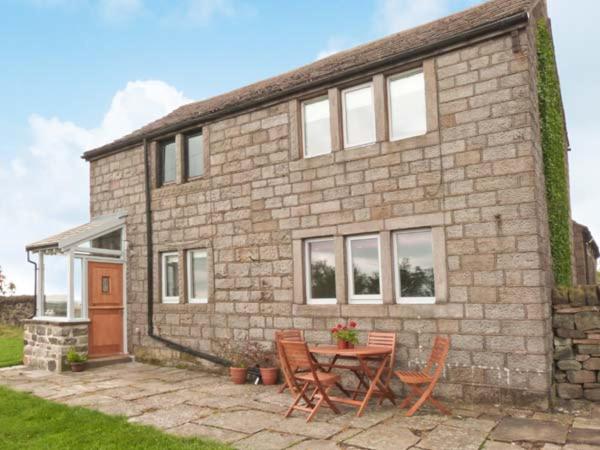 a brick house with a table and chairs in front of it at Knowle Lodge in Mytholmroyd