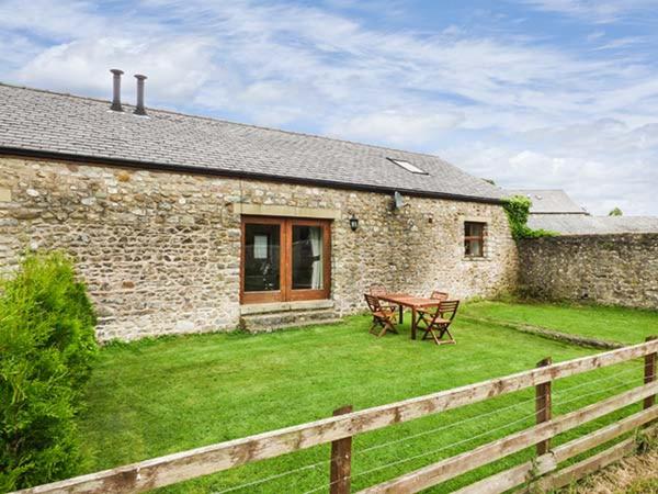 a stone house with a picnic table in the yard at Parsley Cottage in Conder Green