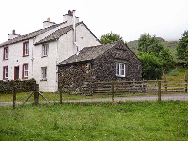 uma casa de pedra com uma cerca em frente em Cockley Beck Cottage em Coniston