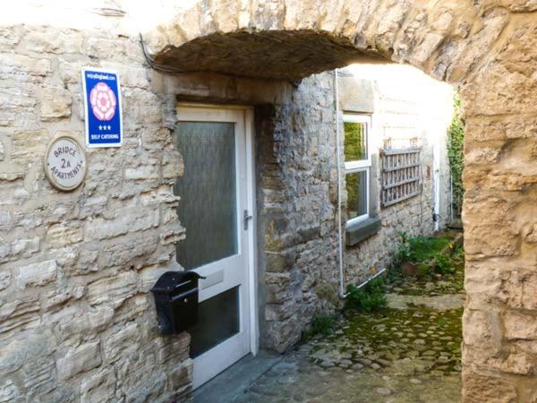 una entrada a un edificio de piedra con puerta en 2A Bridge Apartments en Masham