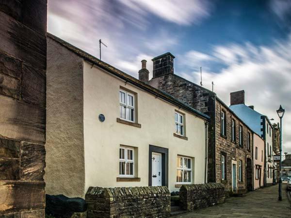 a white building on a street next to a building at Bastle House in Haltwhistle