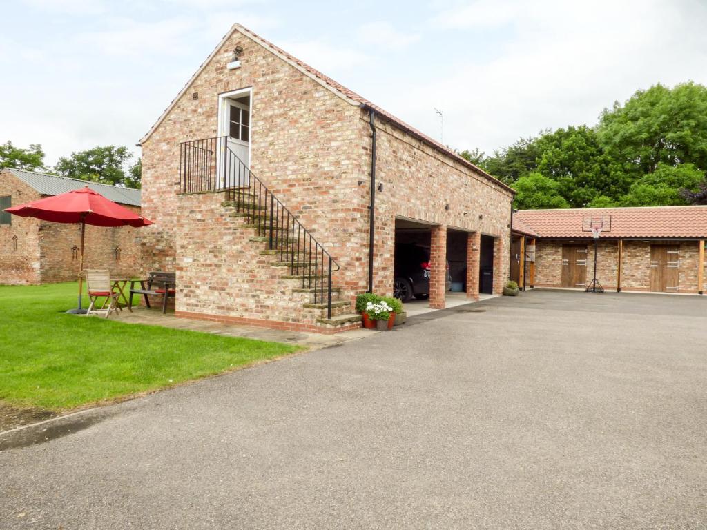 a brick building with a patio and a basketball hoop at The Stables, Crayke Lodge in Crayke