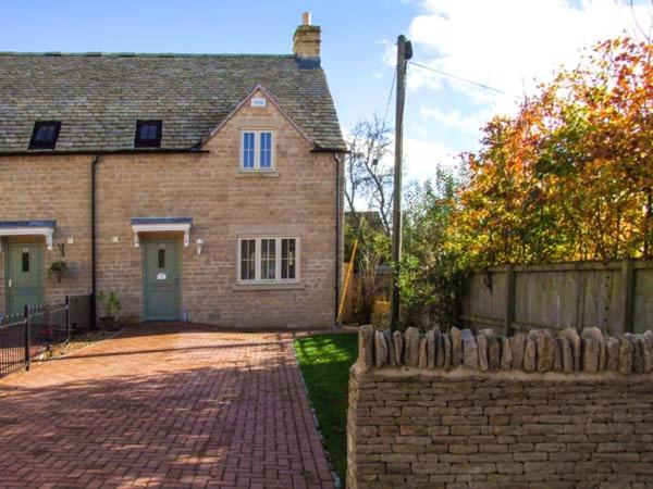 a brick house with a fence and a brick driveway at Jubilee Mews in Andoversford