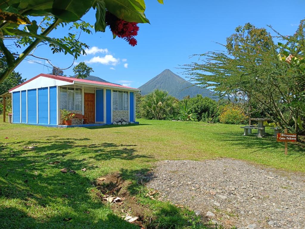 una pequeña casa azul con una montaña en el fondo en Casa de Campo Heliconia, en Fortuna