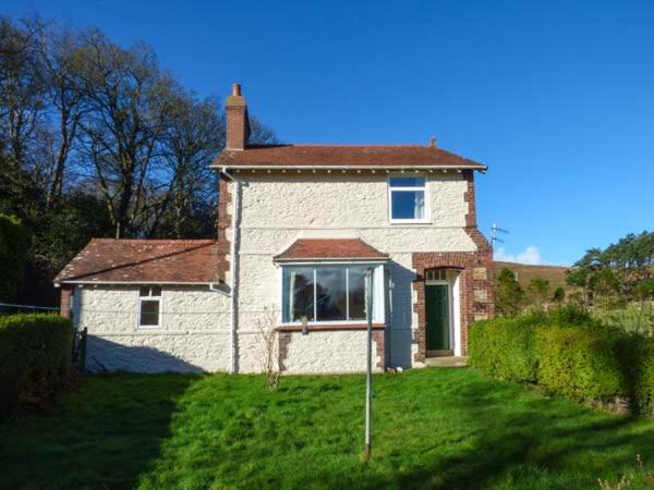 a small brick house with a window on a yard at Pensychnant Cottage in Conwy