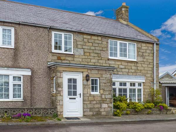 a brick house with a white door and windows at Sandy Knowes in Amble