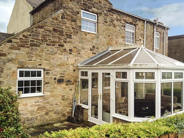 a conservatory in front of a stone house at Laurel Cottage in Leadgate