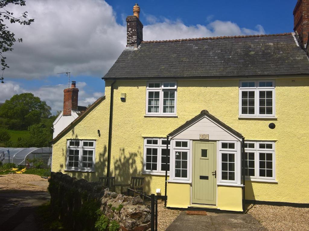 a yellow house with a green door at St Margaret's Cottage in Chardstock