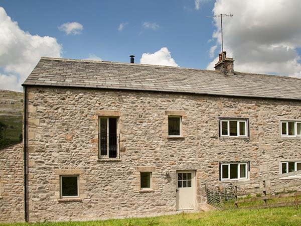 a stone building with a roof on a field at Dale House Farm Cottage in Weathercote