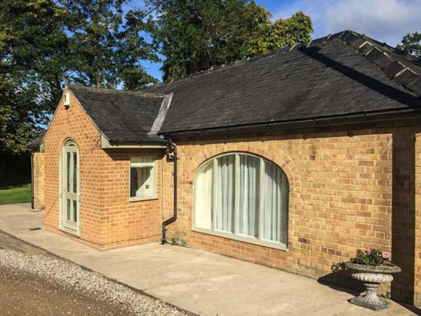 una pequeña casa de ladrillo con ventana y aphalt en Walworth Castle Holiday Cottage en Walworth