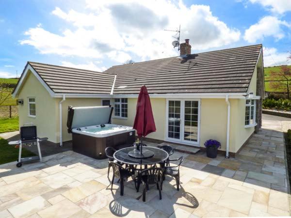 a house with a patio with a table and a tub at Bryn Tirion in Bettws-yn-Rhôs