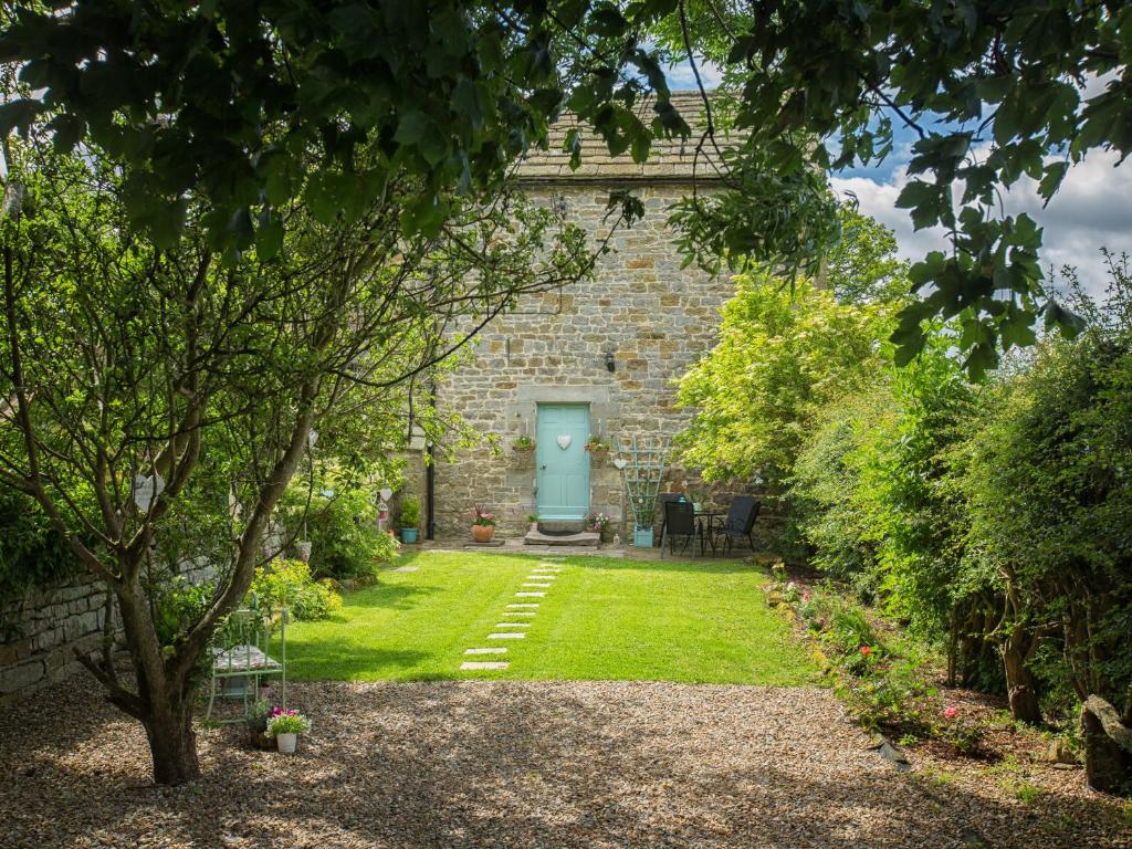 a brick house with a blue door in a yard at West Wing Cottage in Sandhoe