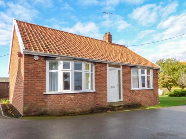 a small red brick house with a white door at Glenhaven in Rendham