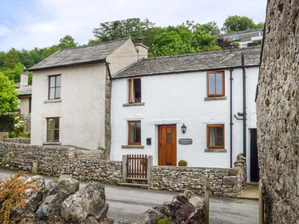 una casa bianca con un muro di pietra davanti di Cinderbarrow Cottage a Levens