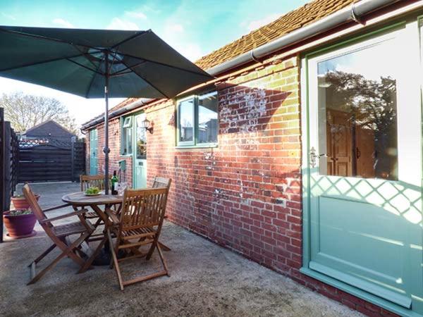 a patio with a table and an umbrella at Stable View in Hingham