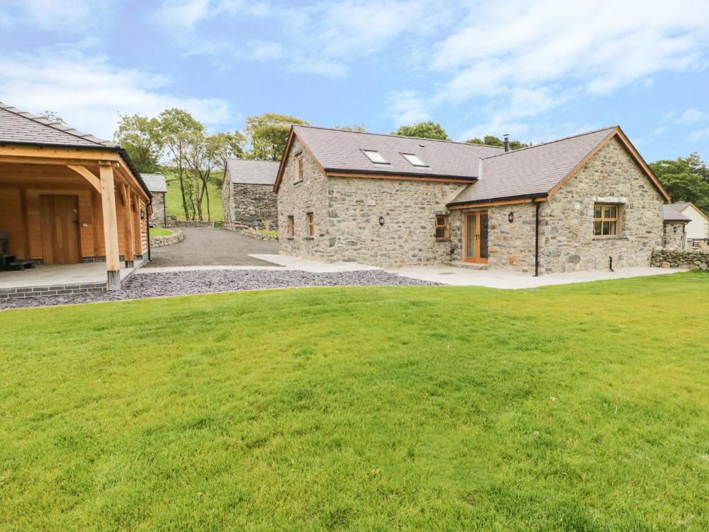 a stone house with a green lawn in front of it at Sgubor in Llangwm