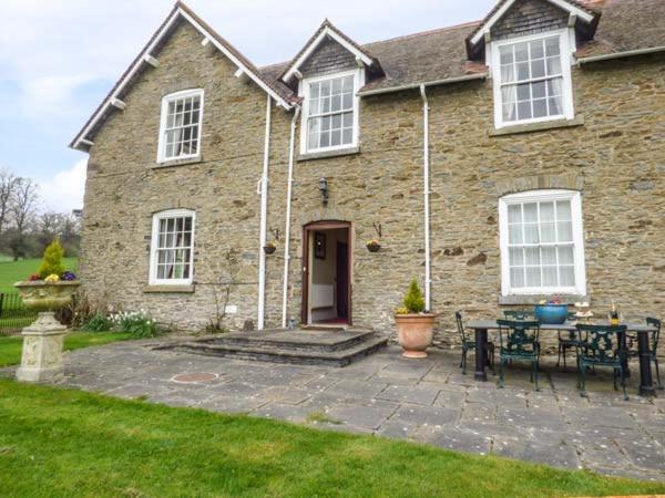 a brick house with a patio and a table at Walcot Farm in North Lydbury