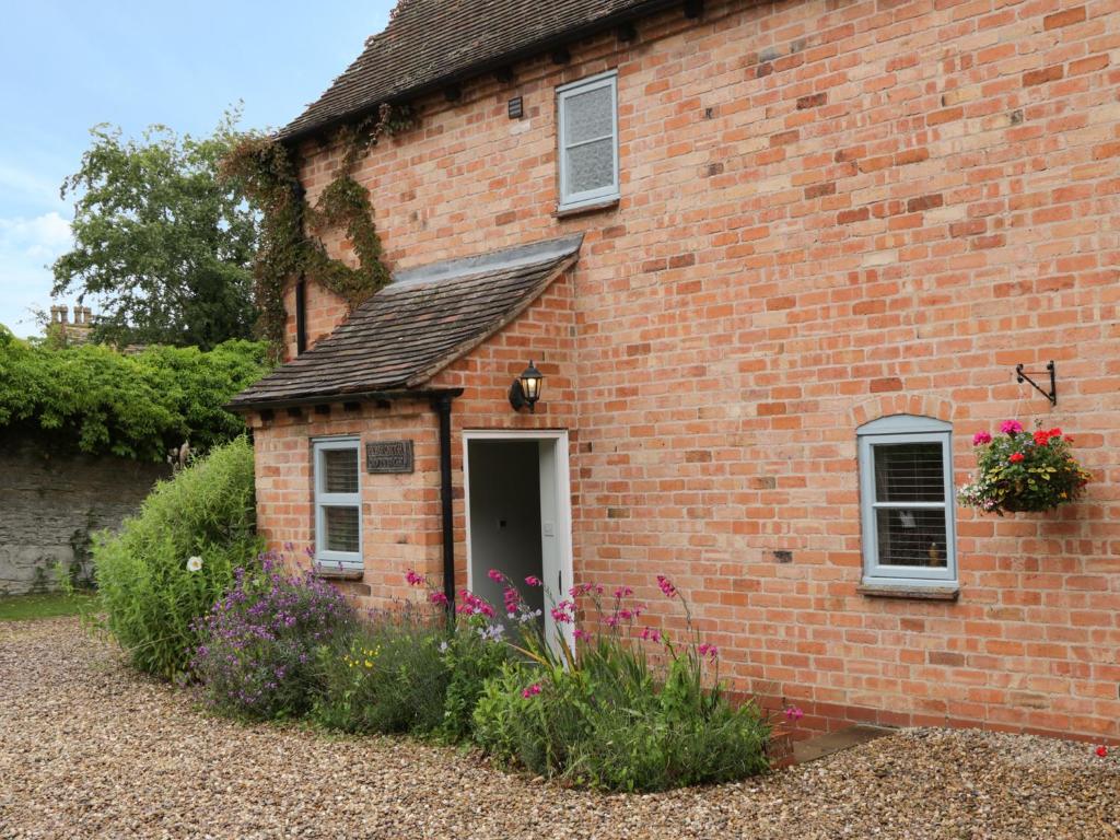 a brick building with a door and some flowers at Pebworth Cottage in Pebworth