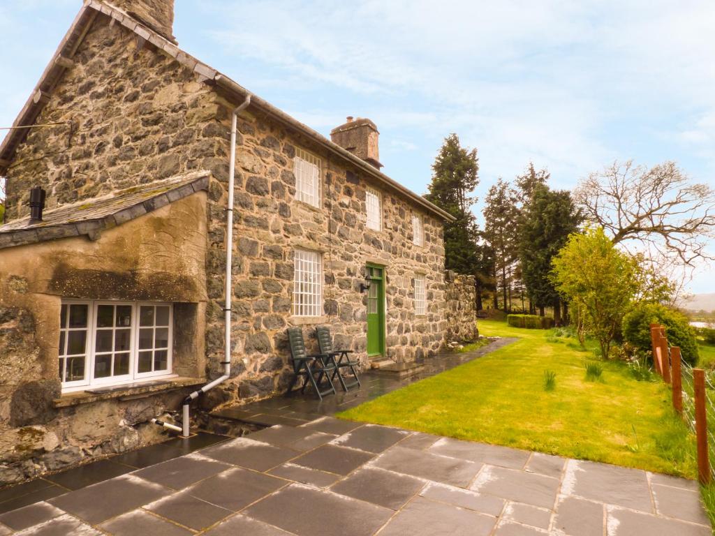 una vecchia casa in pietra con una porta verde e un cortile di Ffynnon Gower a Llangower