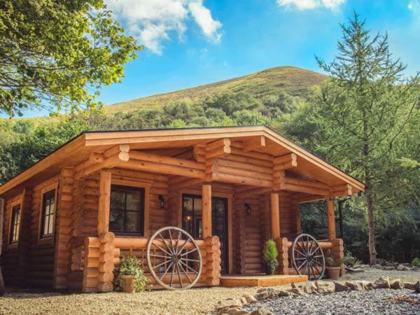 ein Blockhaus mit zwei großen Rädern davor in der Unterkunft Wilderness Lodge in Shelve