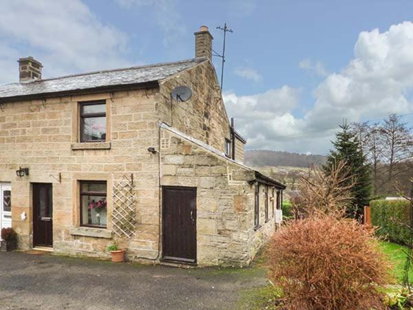 an old stone building with a window and a door at Woods View Cottage in Tansley