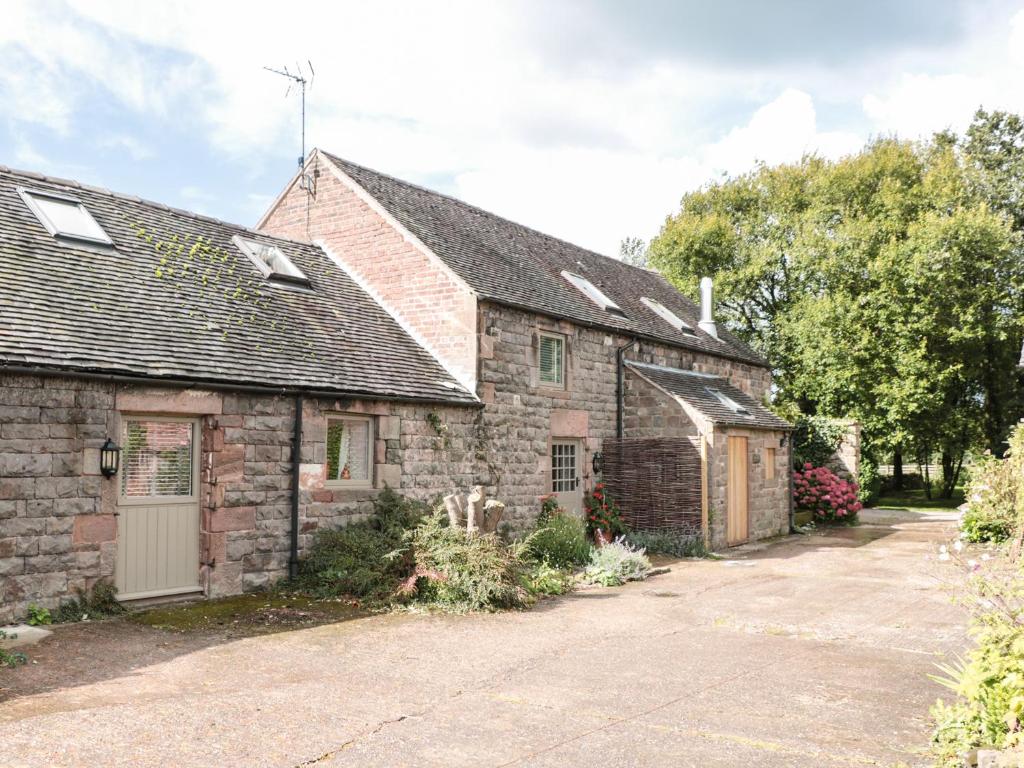 an old stone house with a garage and a driveway at Lee House Cottage in Cheddleton