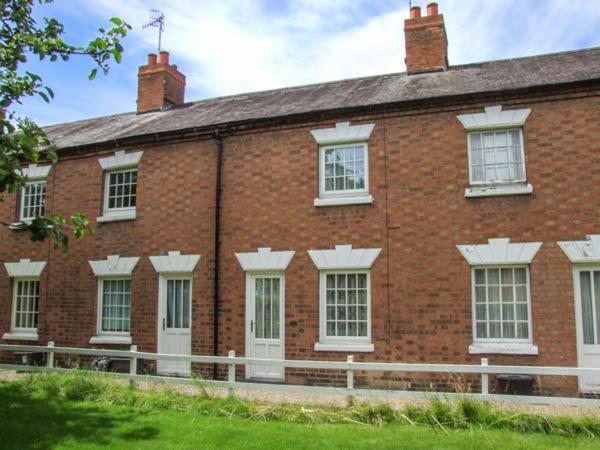 a brick building with white windows and a white fence at 11 Victoria Cottages in Stratford-upon-Avon
