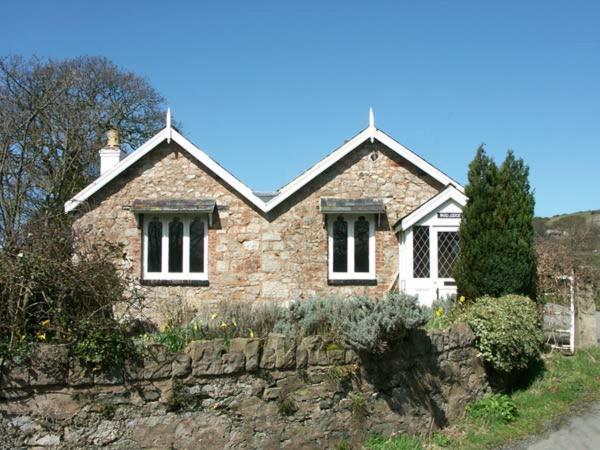 a brick house with a stone wall in front of it at Pabo Lodge in Llandudno Junction