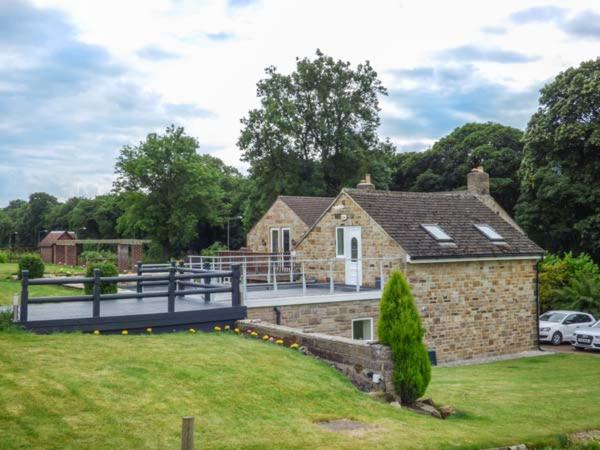 a brick house with a bridge in front of it at Poacher's Rest in Great Rowsley