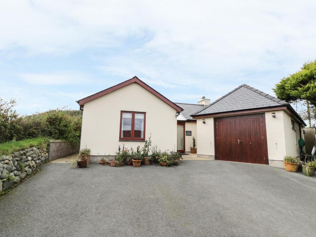 a white house with a garage and a driveway at Manaros Cottage in Aberdaron