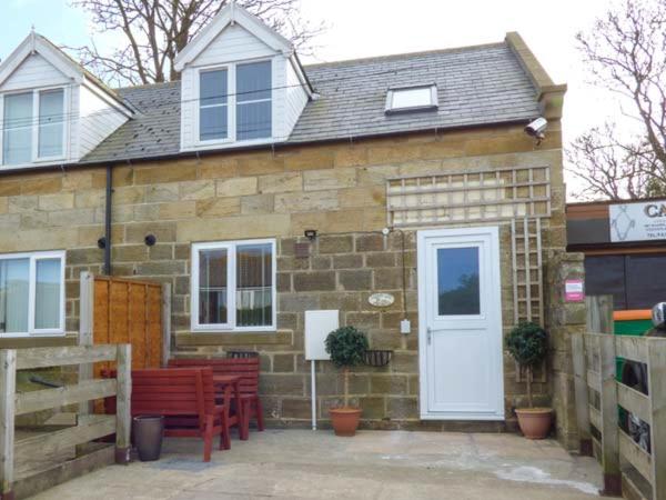 a brick building with red benches and a white door at Fortunatus in Whitby