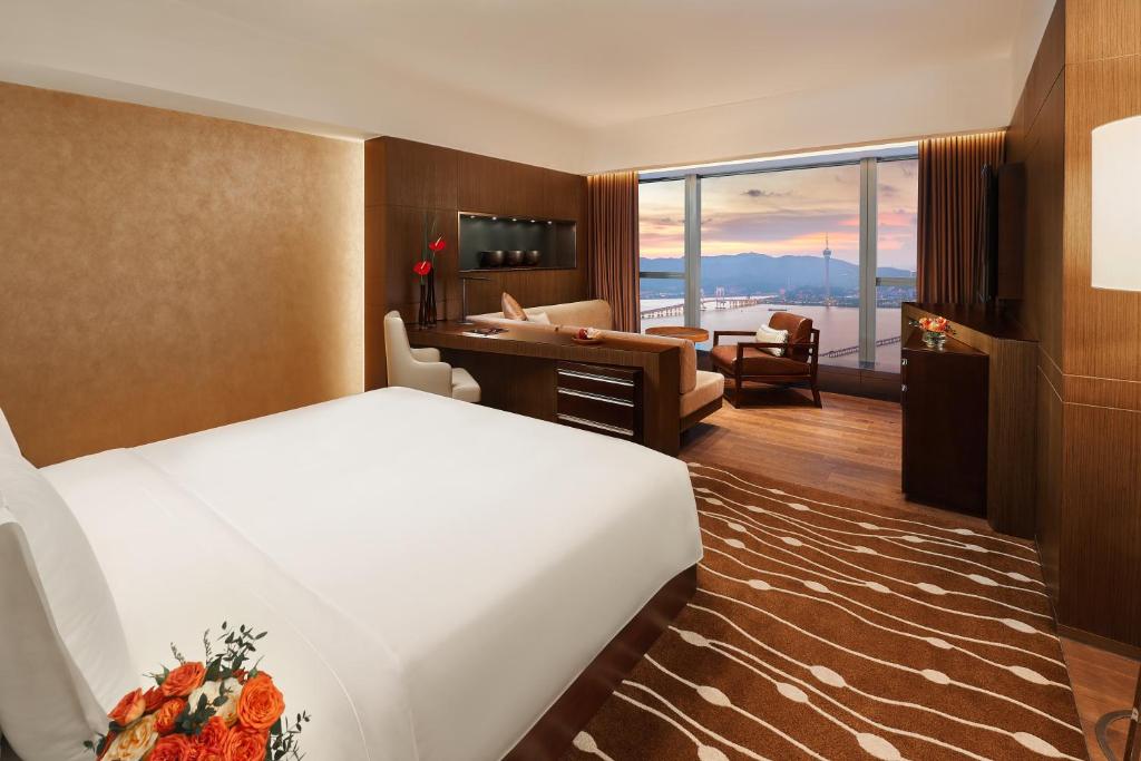 um quarto de hotel com uma cama grande e uma secretária em Altira Macau em Macau