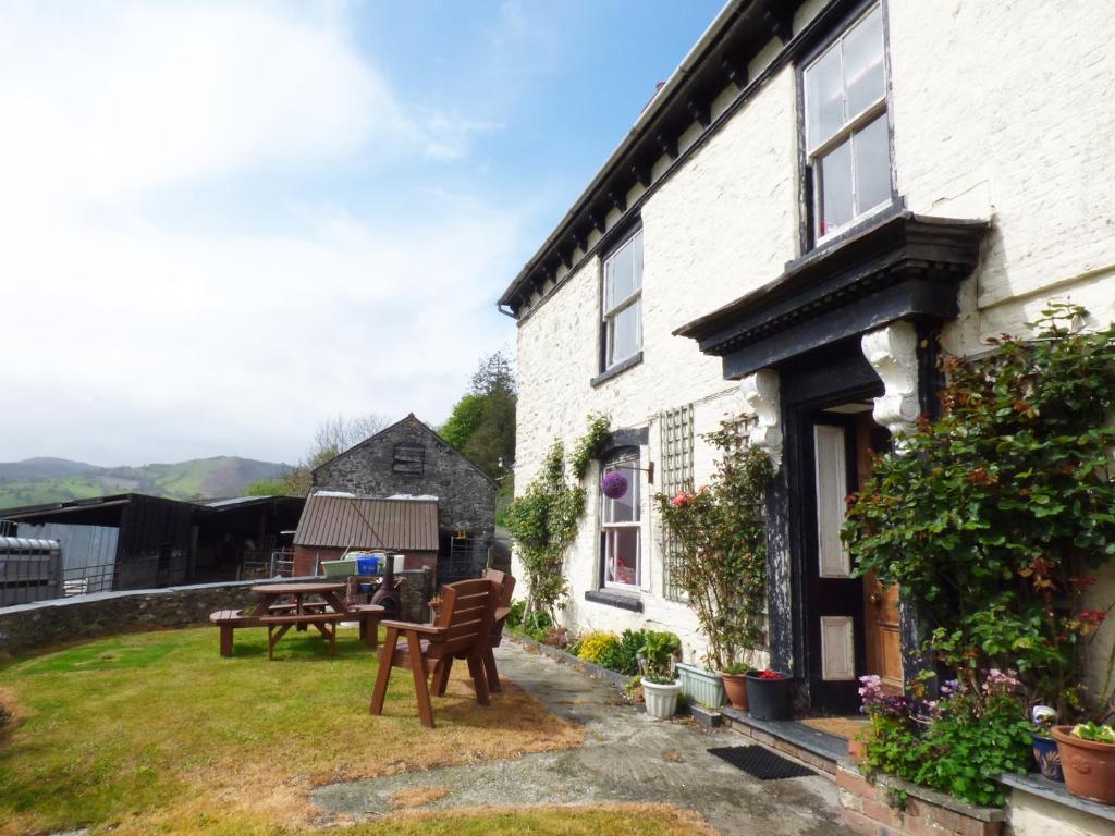 a house with a yard with a table and chairs at Arllen Fawr in Pen-y-bont-fawr