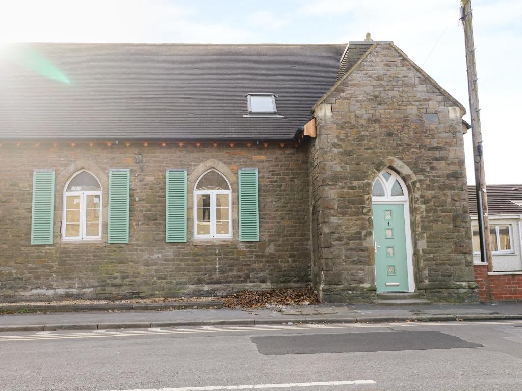 a brick building with a green door on a street at No 1 Church Cottages in Llanelli