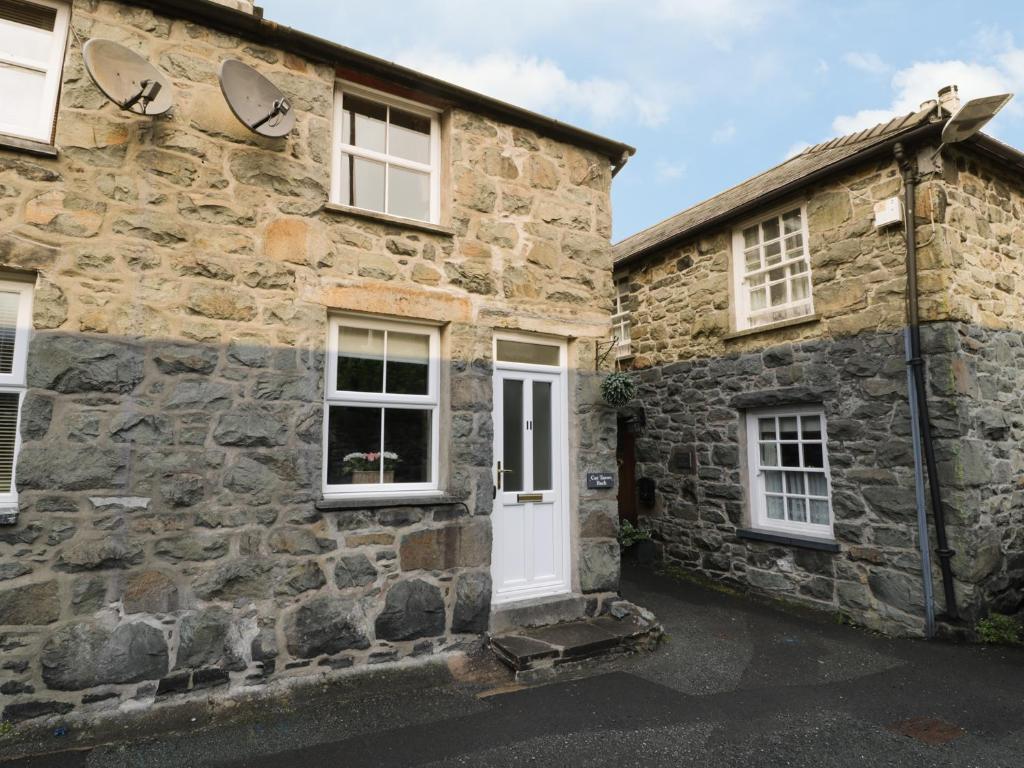 a stone house with a white door and windows at Cae Tanws Bach in Dolgellau