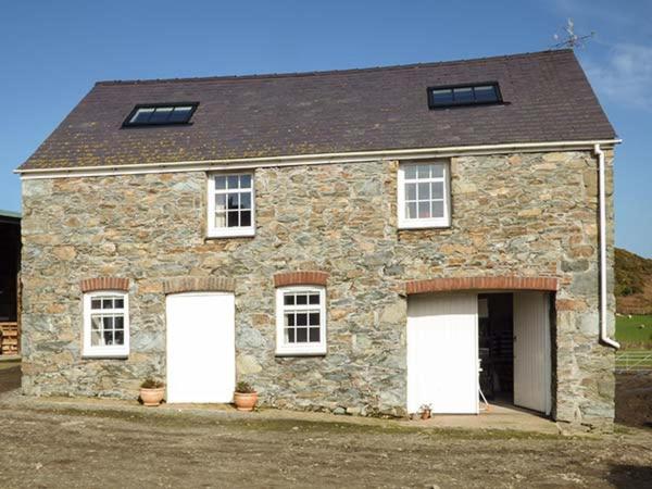 a stone house with two white garage doors at Bran Goesgoch in Holyhead