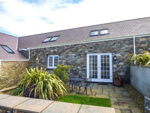 Casa de piedra con patio con mesa y sillas en Y Wylan, en Holyhead