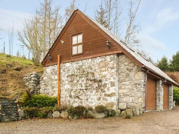 a small stone building with a brown roof at Lakefield Apartment in Bearnock