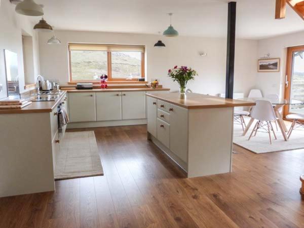 a large kitchen with white cabinets and a wooden floor at Skipaflotta in Rhiconich